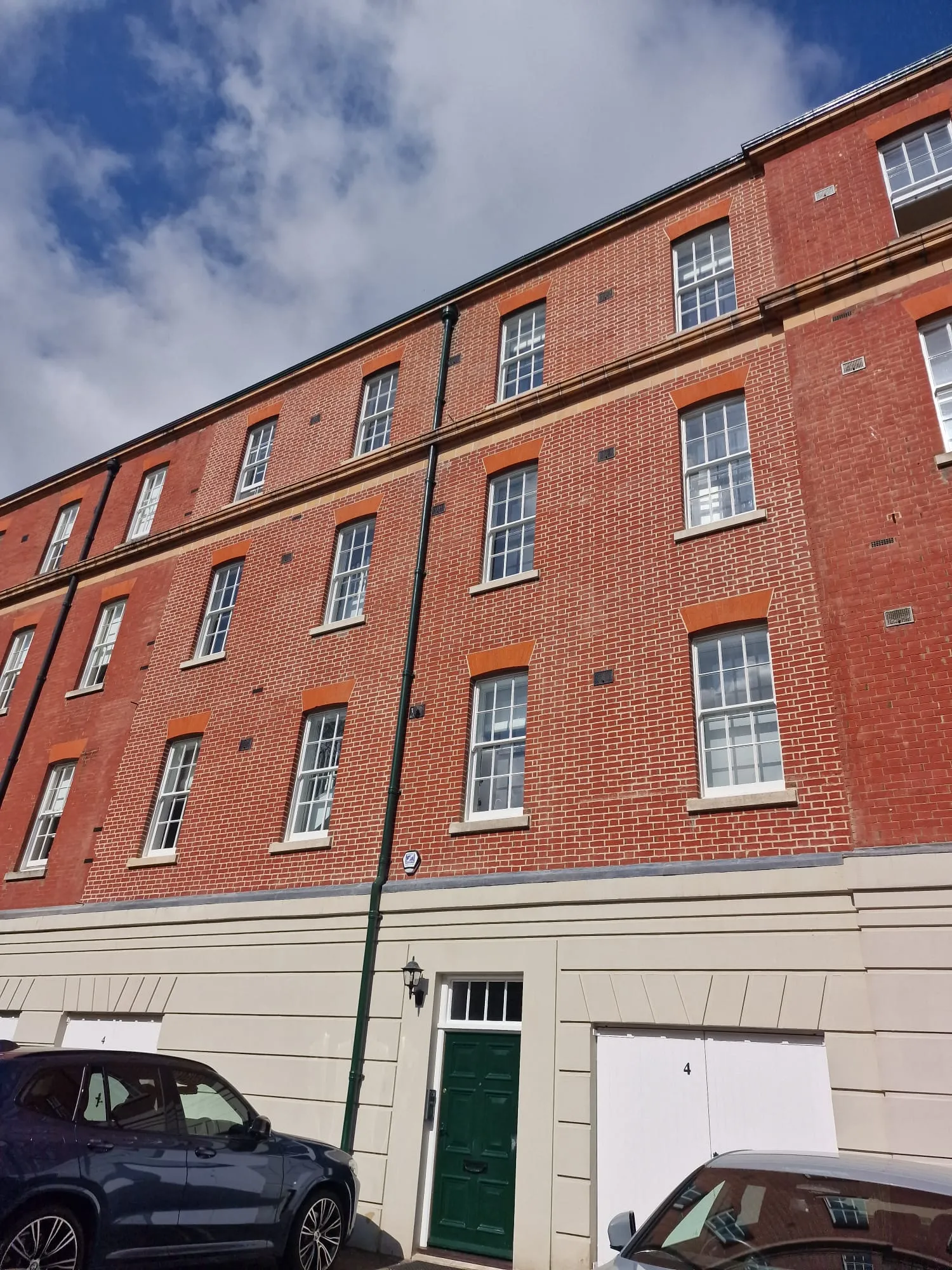 Two cars parked in front of a tall brick building.