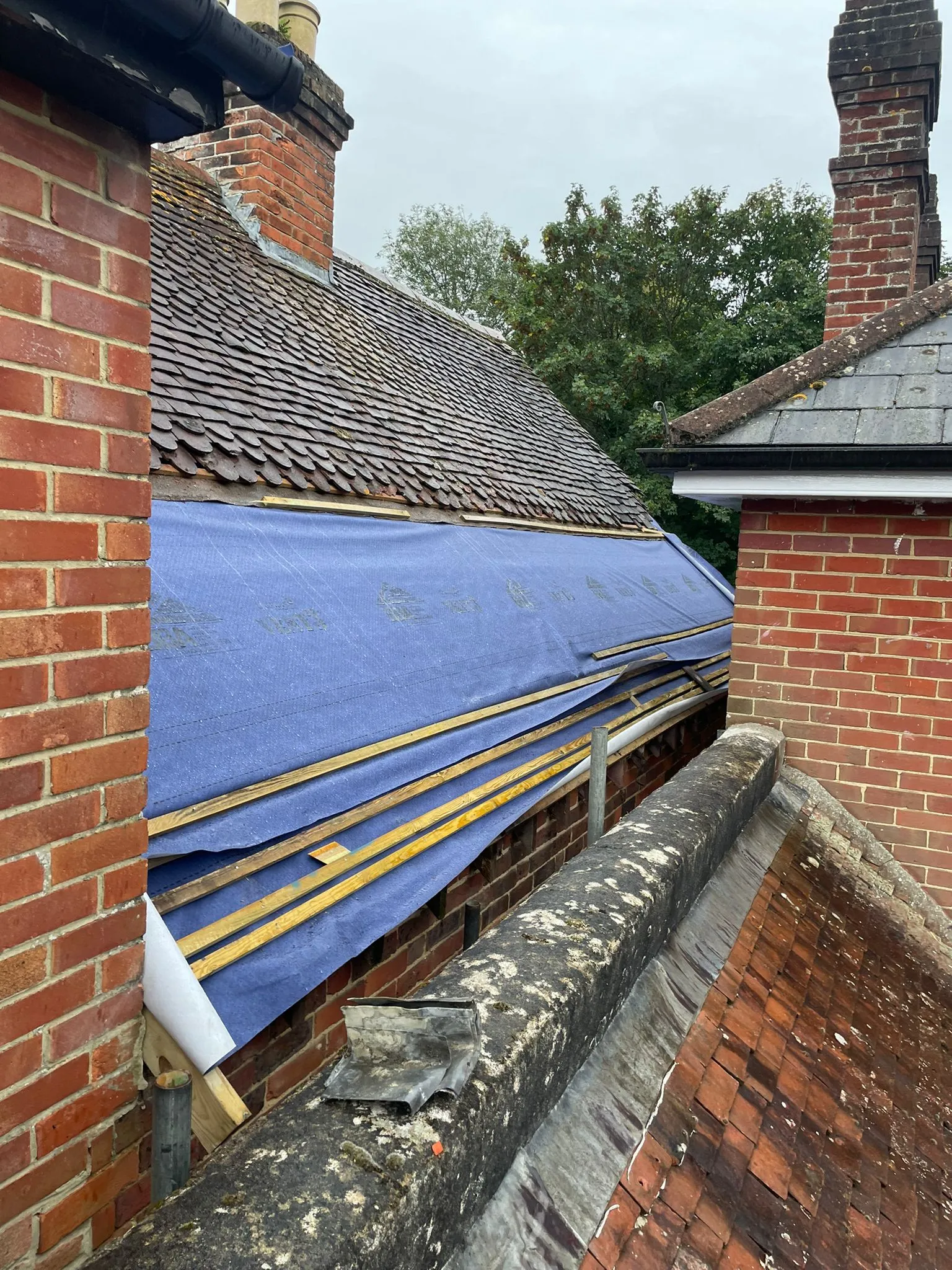 A blue tarp covering the roof of a brick building.