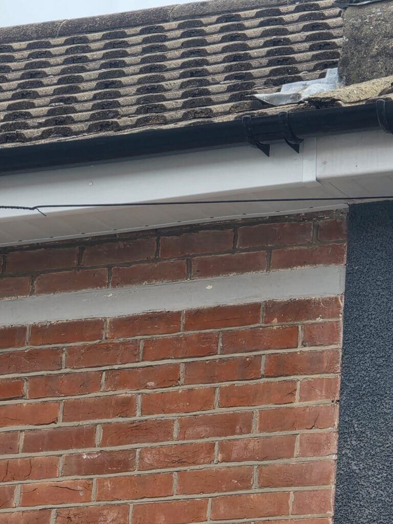 New white uPVC fascia and soffit board with black guttering on a brick house in Portsmouth